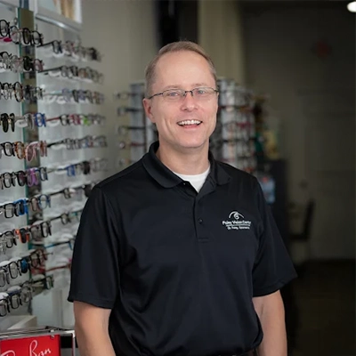 Matthew Foley smiling while standing by a wall of glasses.